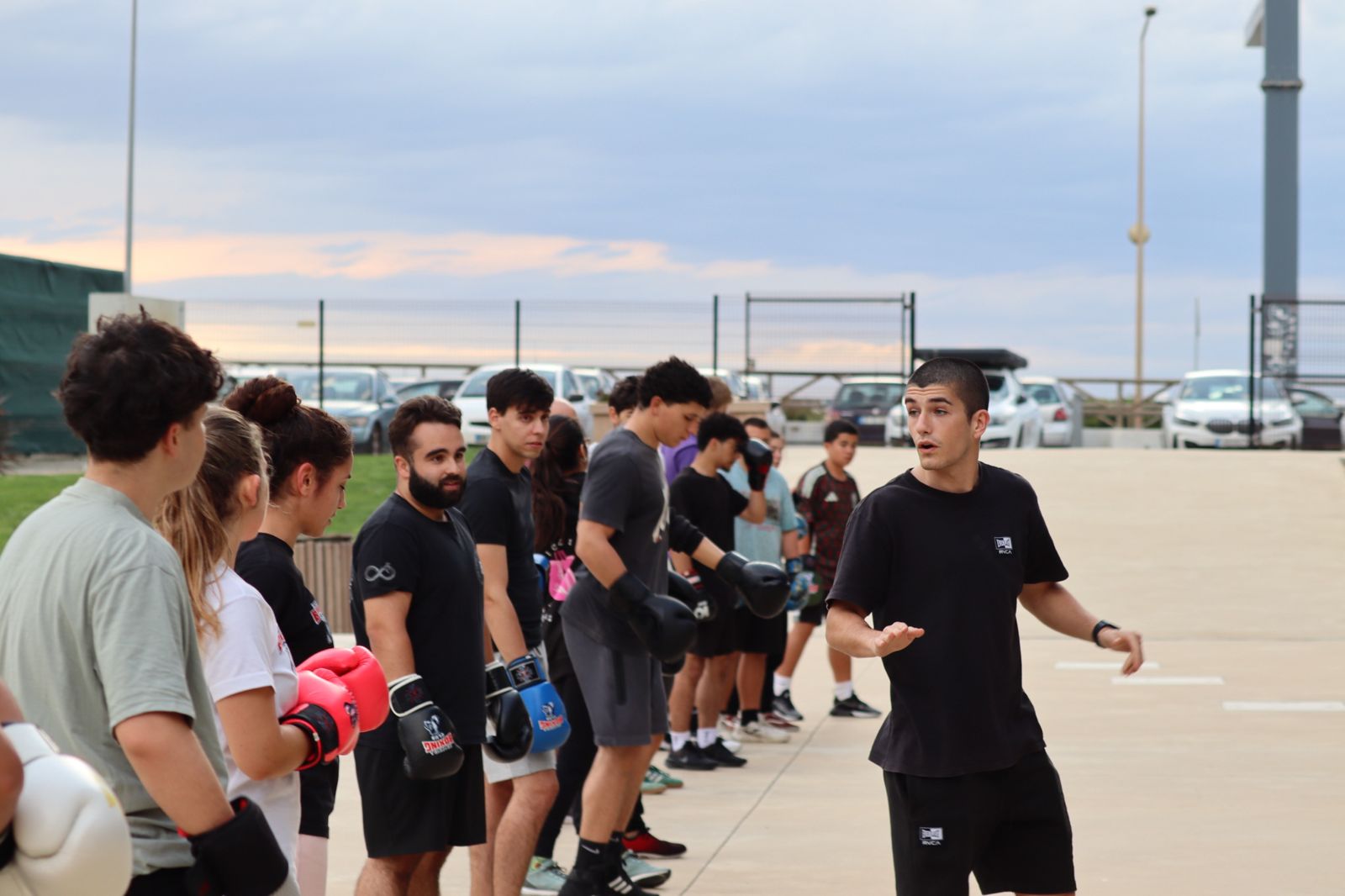 Treinador a explicar um exercício a uma fila de atletas de luvas calçadas